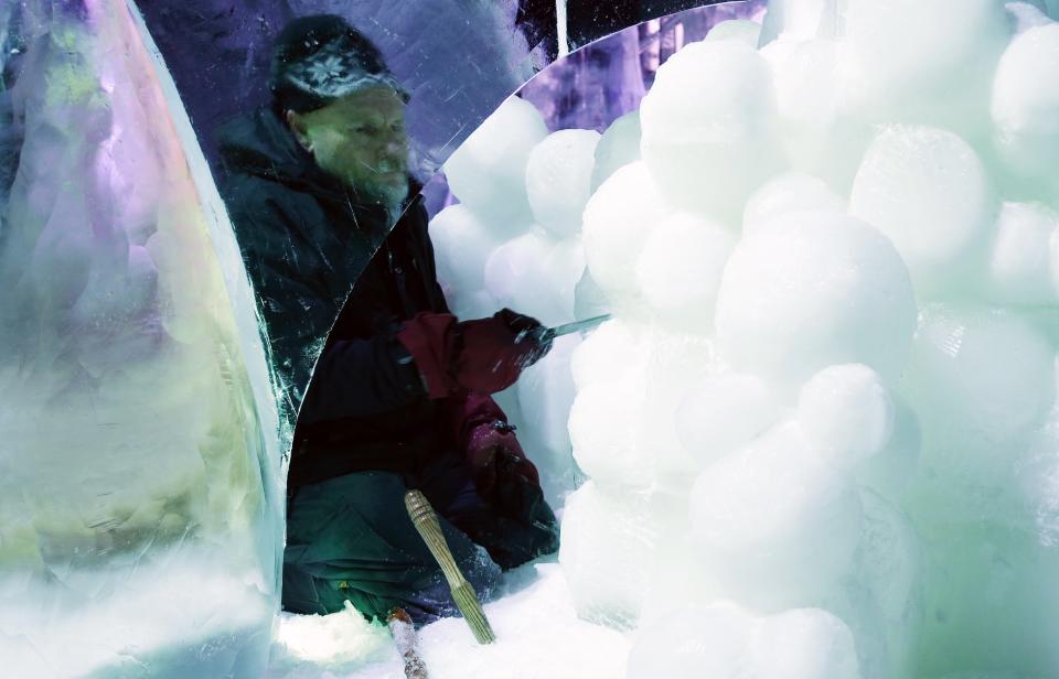 Sculptor Partanen of Finland carves a sculpture near characters of comic strips at the Brussels Ice Magic Festival