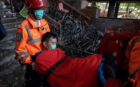 A man is evacuated by medics past charred debris from the Polytechnic University in Hong Kong on Wednesday, Nov. 20, 2019 - Credit: AP