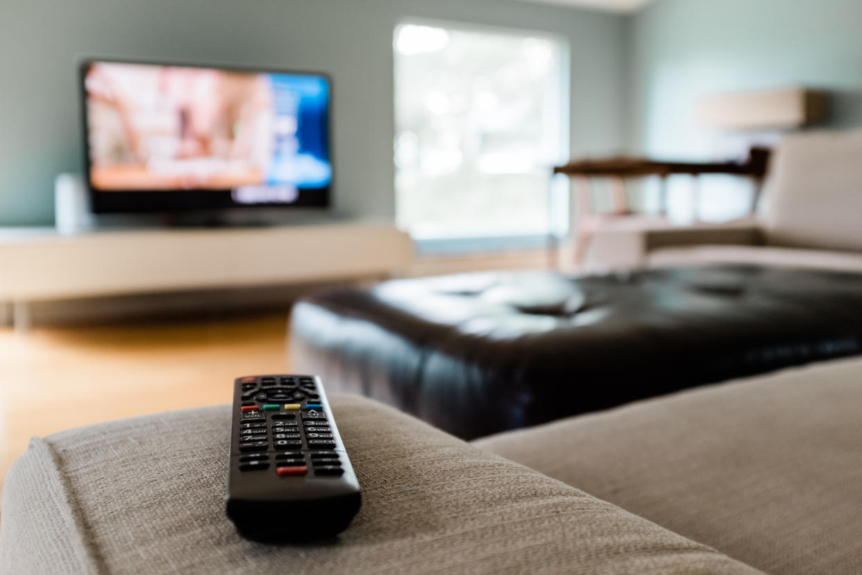 Close-up of a remote control sitting on a couch in an empty modern living room.