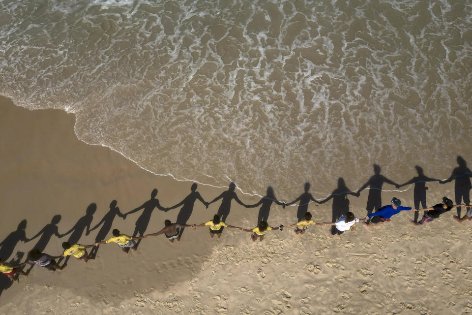 Varias personas forman una cadena humana en la costa de Sao Conrado para abrazar de forma simbólica el mar con motivo del Día de los Océanos, en Río de Janeiro, Brasil, el 8 de junio de 2023. (AP Foto/Bruna Prado)