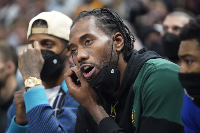 Los Angeles Clippers' Paul George, left, and Kawhi Leonard, right, look on from the bench.