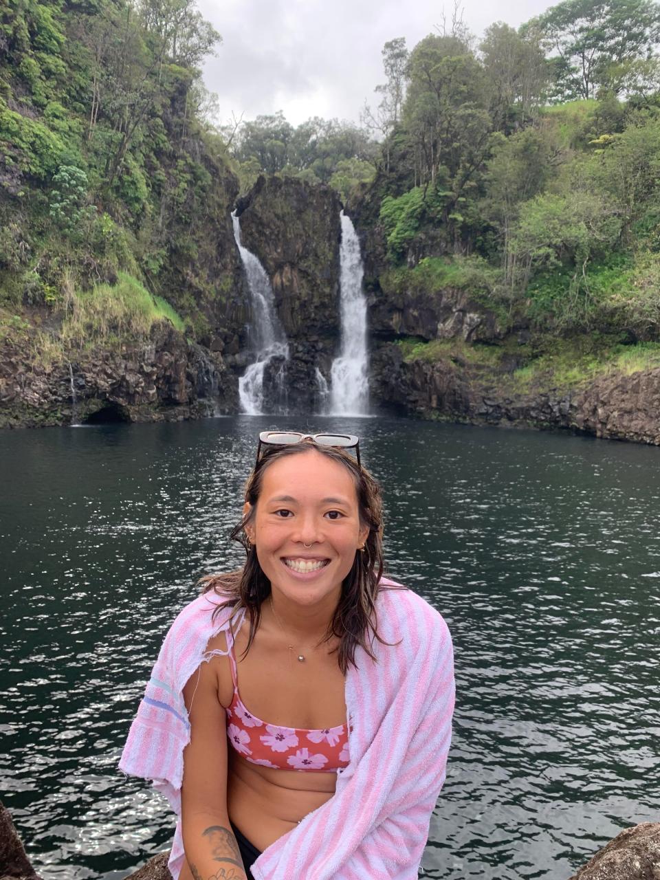 A woman posing for a picture wrapped in a town in front of a waterfall in Hawaii