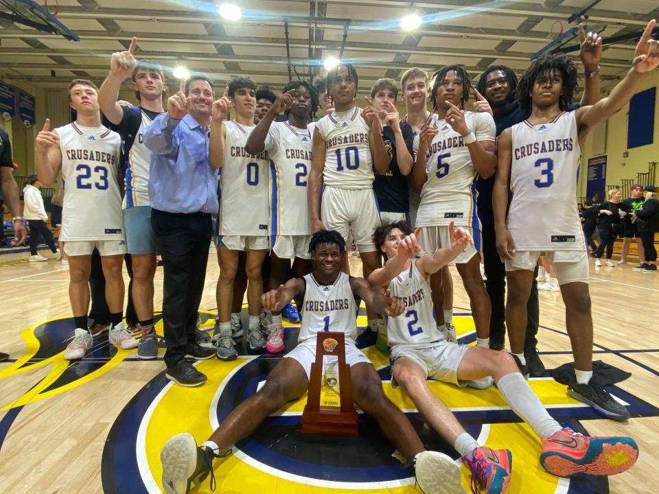 Cardinal Newman’s boys basketball team posed with their first district championship trophy since 2016 after a 74-60 win against rival King’s Academy.