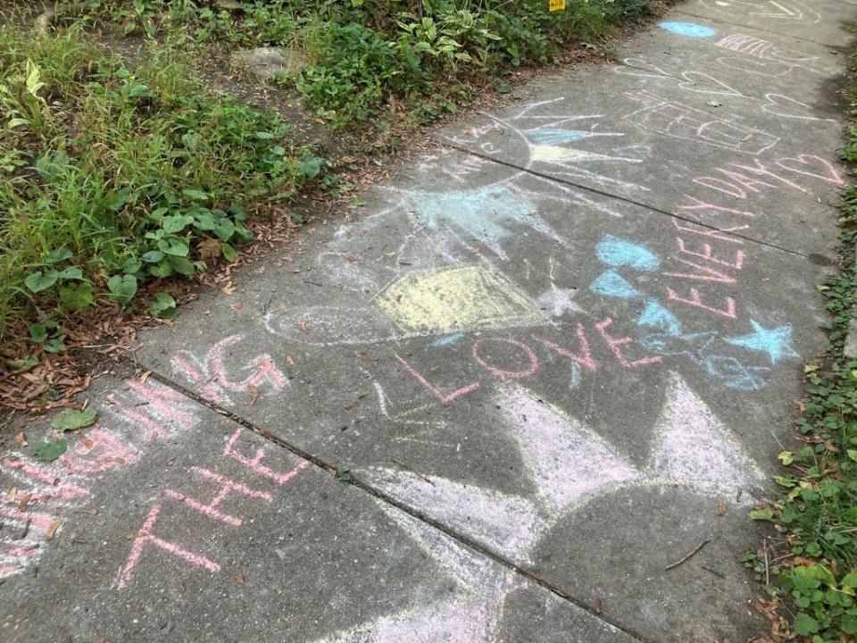 A chalk drawing that says "Bringing the love every day" on a Riverwest sidewalk is a tribute to "Mailman Mike" Boothe.