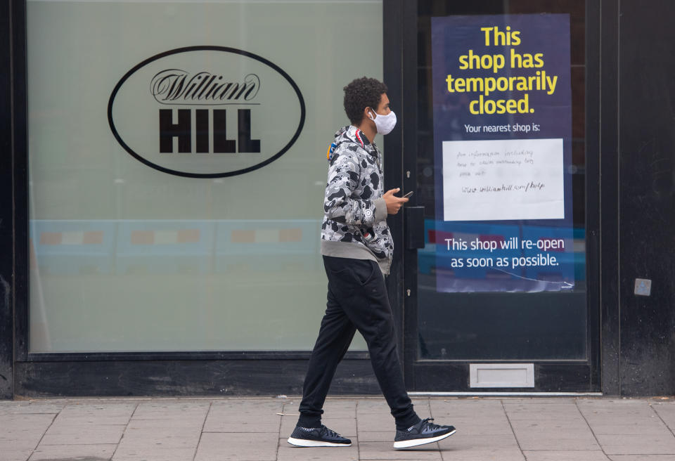 A man passes a closed branch of bookmakers William Hill in Waterloo, London, following the introduction of measures to bring England out of lockdown. (Photo by Dominic Lipinski/PA Images via Getty Images)