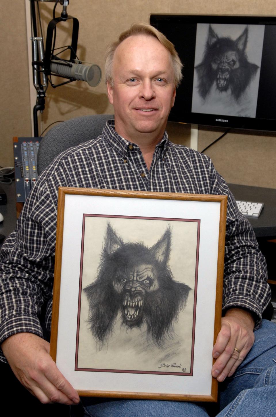 Steve Cook poses with a print of what the Dogman might look like in his studio office at radio station WTCM on Oct. 26, 2011. The local legend has become popular through Cook and his story and song about the alleged existence of the man/dog.