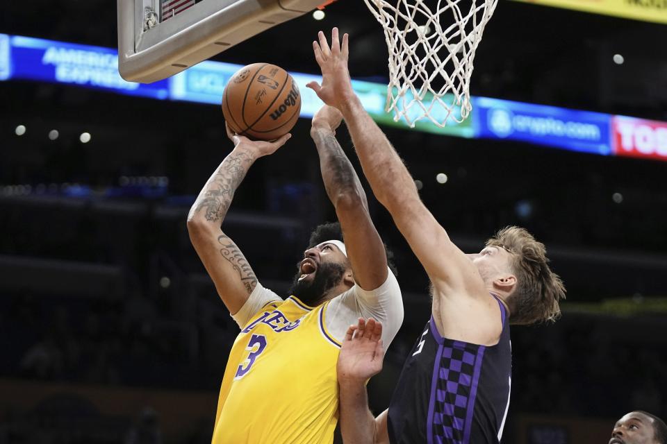 Los Angeles Lakers forward Anthony Davis, left, shoots as Sacramento Kings forward Domantas Sabonis defends during the first half of an NBA basketball game Wednesday, Nov. 15, 2023, in Los Angeles. (AP Photo/Mark J. Terrill)