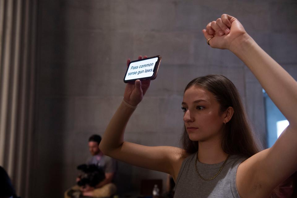 Natalie Schilling holds a phone up reading ‘Pass common sense gun laws” in the House Chamber gallery at the State Capitol Building in Nashville , Tenn., Tuesday, Aug. 22, 2023.