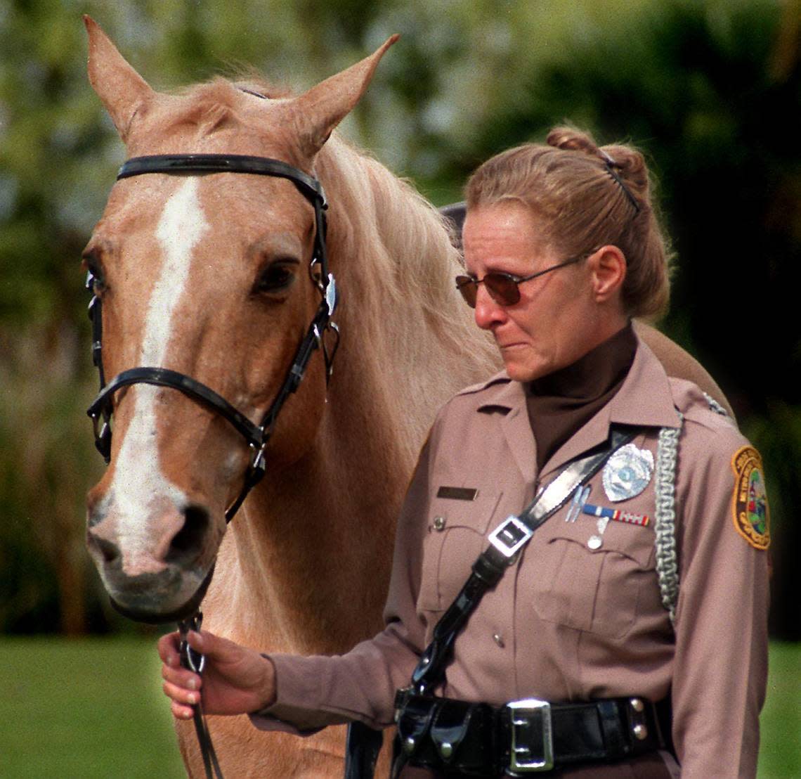 to nabes-12/10/98-natale planas-Metro Dade Mounted Police Officer Kathy Wyche, with her horse Dusty, holds back tears at the retirement ceremony held for three Metro Dade horses Thursday at Tropical Park.