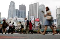 FILE PHOTO: People cross a street in front of high-rise buildings in the Shinjuku district in Tokyo