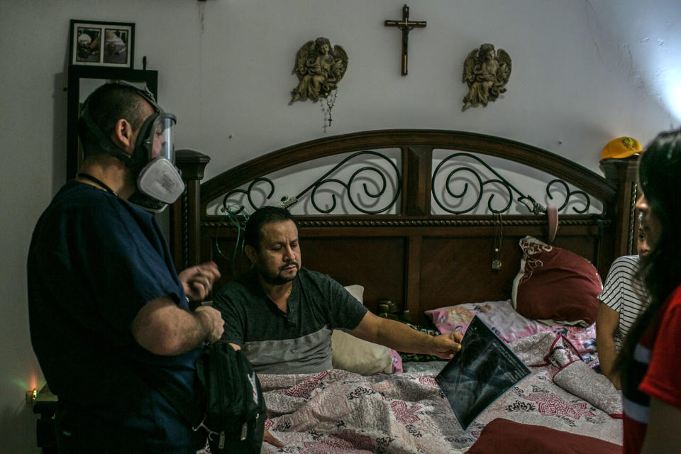 Gutiérrez responde al mensaje de un paciente sentado en su patio trasero, rodeado de vecinos. (Meghan Dhaliwal/The New York Times)