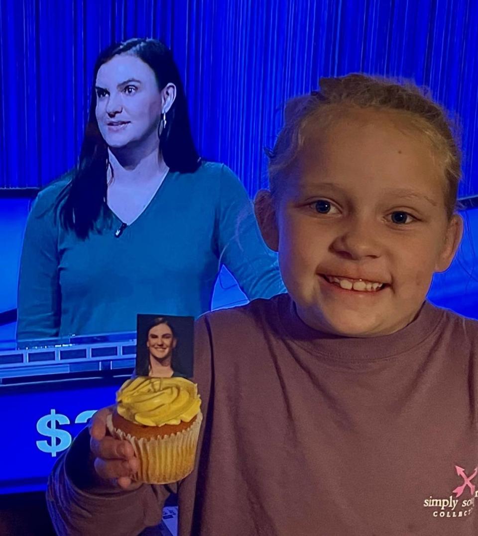 Ginny Dees holds up a cupcake celebrating her cousin Clark Dawson appearing on ‘Jeopardy.’ Extended family watched together via Zoom.
