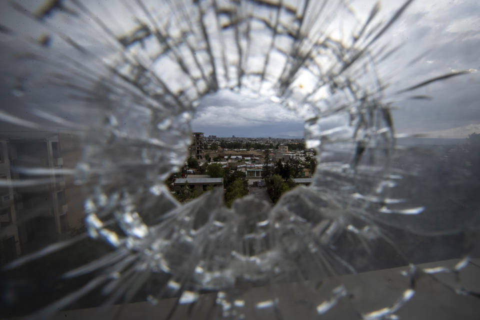 The city of Mekele is seen through a bullet hole in a stairway window of the Ayder Referral Hospital, in the Tigray region of northern Ethiopia, on Thursday, May 6, 2021. While the government now holds many urban centers, fierce fighting continues in remote rural towns. (AP Photo/Ben Curtis)