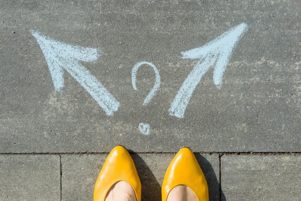 Female legs with 2 arrows and question mark, painted on the asphalt.