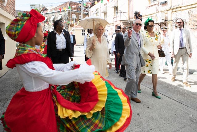 The Prince of Wales and the Duchess of Cornwall watch dancers during a walkabout through the streets of St George’s 