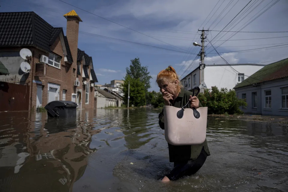 A local resident makes her way through a flooded road after the walls of the Kakhovka dam collapsed overnight