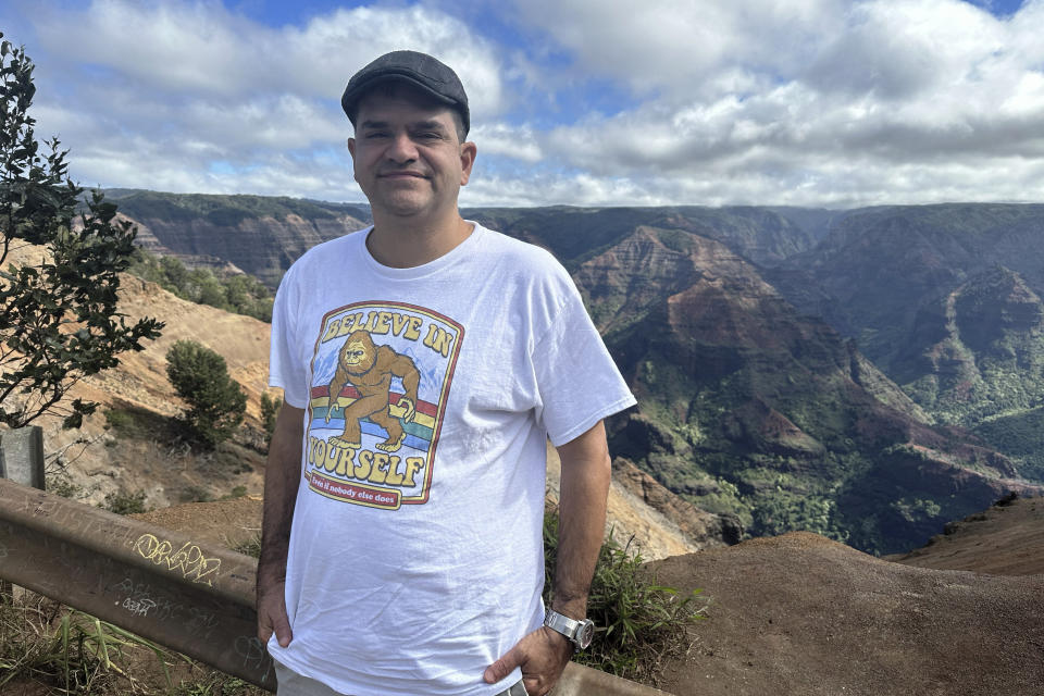 Antonio Perez stands for a portrait in front of Waimea Canyon in Kauai, Hawaii on Nov. 5, 2023. “I think I got a sense of self-importance” from conspiracy theories, Perez said. He believed that he alone “was figuring everything out. It all ties into wanting to be a hero.” (AP Photo/Eugene Garcia)