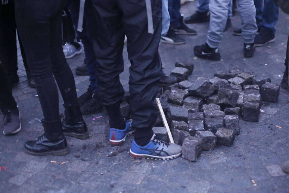 Youths stand by cobblestones during a demonstration Tuesday, Dec. 10, 2019 in Paris. French airport employees, teachers and other workers joined nationwide strikes Tuesday as unions cranked up pressure on the government to scrap upcoming changes to the country's national retirement system. (AP Photo/Thibault Camus)