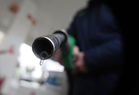 A customer holds a nozzle to fill up his tank in a gasoline station in Nice December 5, 2014. REUTERS/Eric Gaillard/Files