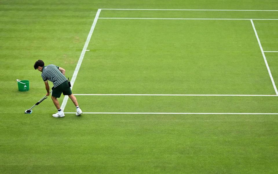 A member of the ground staff cleans the grass from the paint on court 2 on the third day of the 2023 Wimbledon Championships at The All England Tennis Club in Wimbledon, southwest London, on July 5, 2023