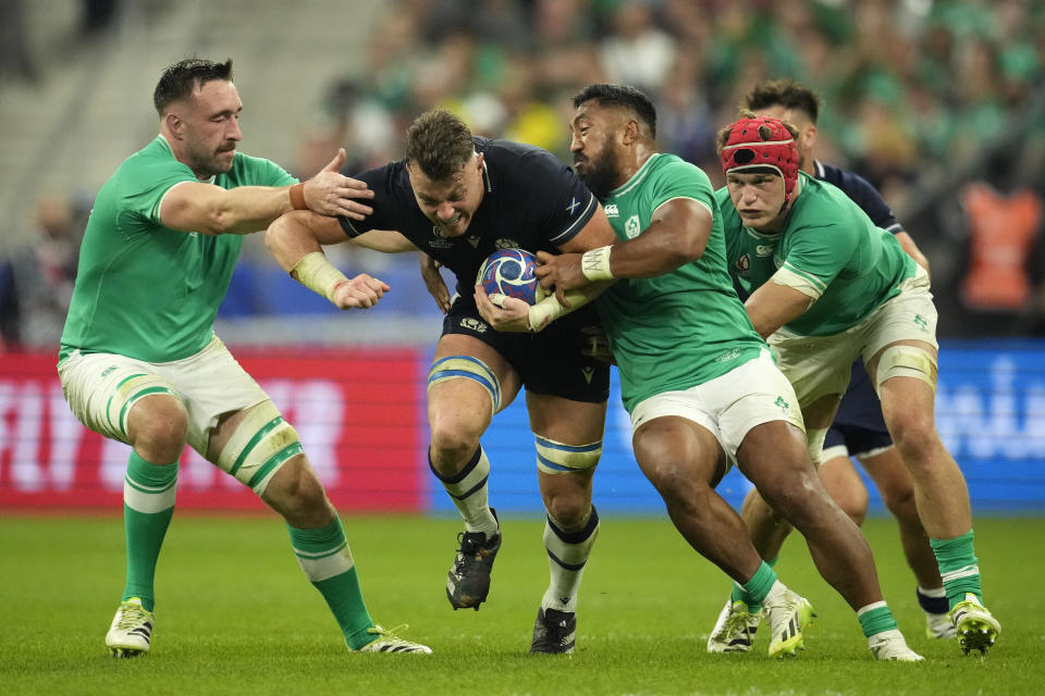 Scotland's Jack Dempsey, center, is tackled by Ireland's Josh van der Flier, right, and Ireland's Bundee Aki, second right, during the Rugby World Cup Pool B match between Ireland and Scotland at the Stade de France in Saint-Denis outside of Paris, Saturday, Oct. 7, 2023. (AP Photo/Christophe Ena)