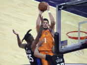 Phoenix Suns guard Devin Booker (1) shoots over New York Knicks forward Reggie Bullock (25) and center Taj Gibson during the first half of an NBA basketball game Friday, May 7, 2021, in Phoenix. (AP Photo/Rick Scuteri)