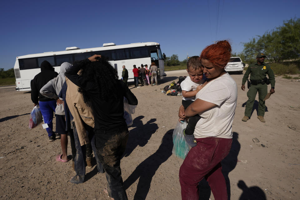 Migrants wait to board busses as they are processed by the U.S. Customs and Border Patrol after they crossed the Rio Grande and entered the U.S. from Mexico, Thursday, Oct. 19, 2023, in Eagle Pass, Texas. Starting in March, Texas will give police even broader power to arrest migrants while also allowing local judges to order them out of the U.S. under a new law signed by Republican Gov. Greg Abbott. (AP Photo/Eric Gay)