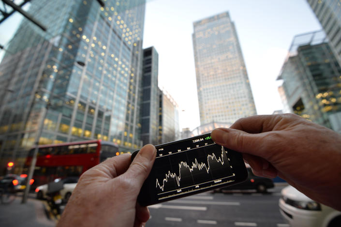 FTSE  A person views share prices on an Iphone, with London&#39;s Canary Wharf in the background.