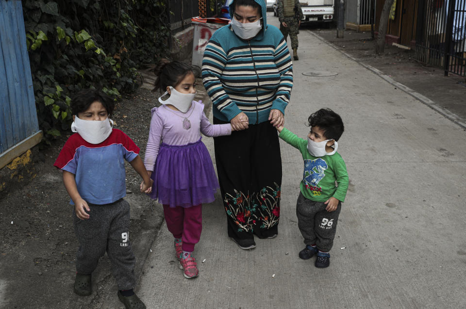 A mother walks out with her children to where an army kitchen was serving food for people who are facing hardship because of lost income due to the new coronavirus pandemic, in Maipu, on the outskirts of Santiago, Chile, Tuesday, June 16, 2020. (AP Photo/Esteban Felix)