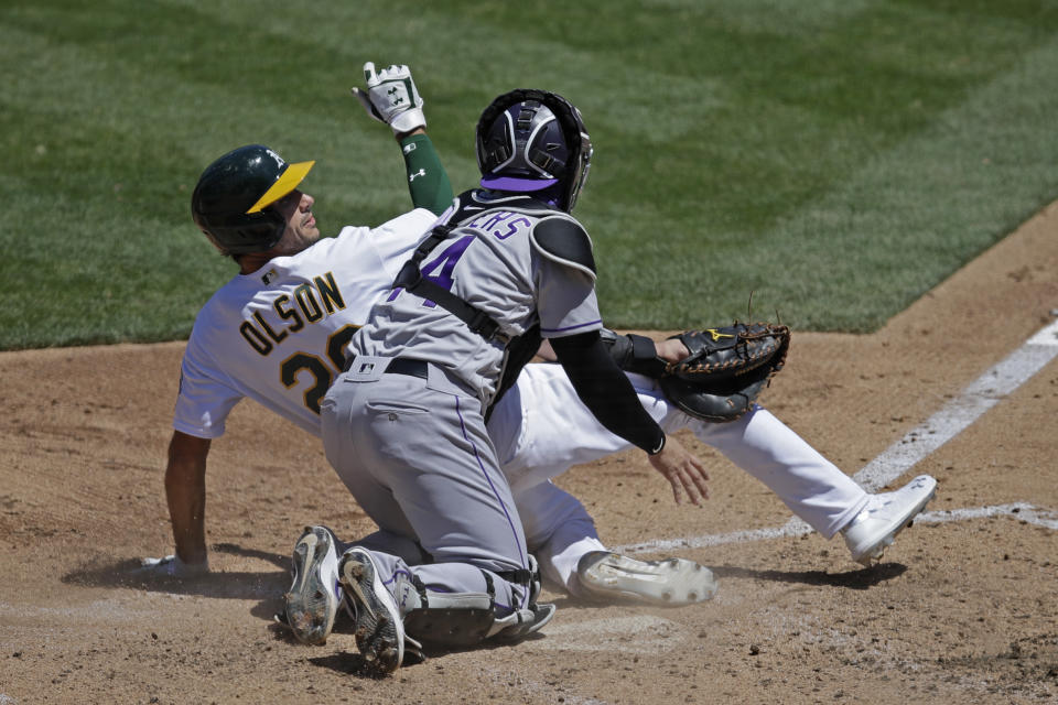 Colorado Rockies catcher Tony Wolters (14) tags out Oakland Athletics' Matt Olson, left, during the fourth inning of a baseball game Wednesday, July 29, 2020, in Oakland, Calif. (AP Photo/Ben Margot)