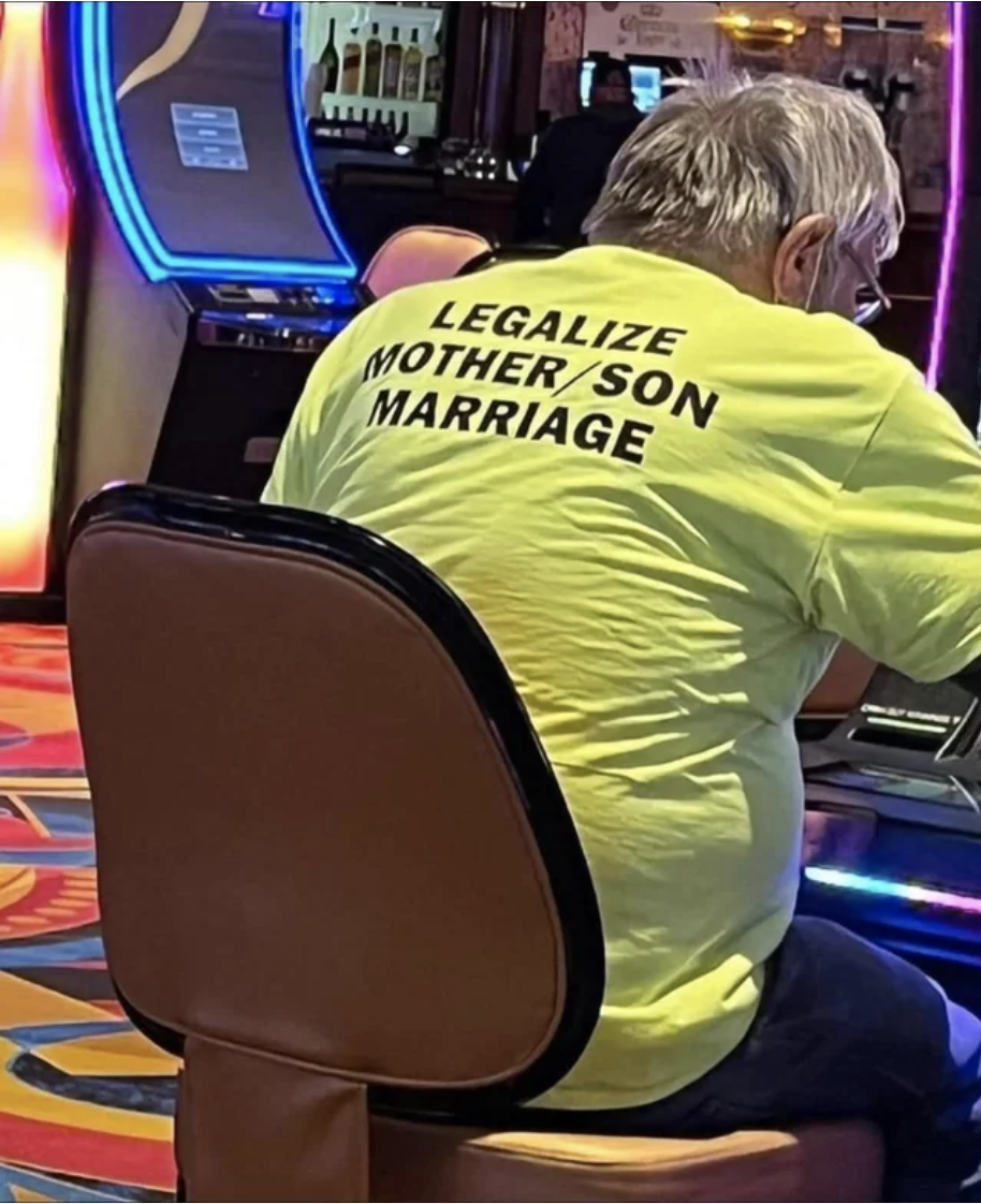 A person sitting in a casino with a T-shirt that says "Legalize mother/son marriage" on the back