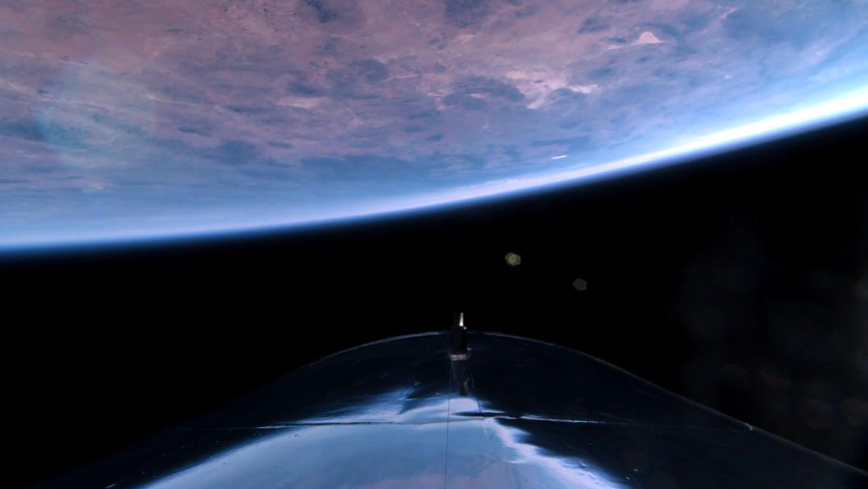  The curve of earth against the blackness of space, with part of a silvery spacecraft in the foreground. 