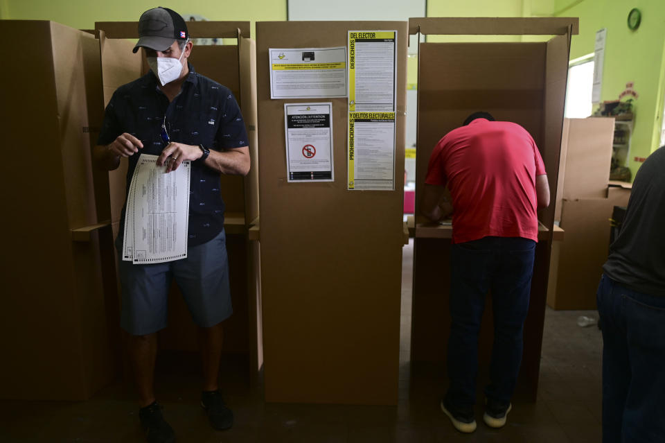 Voters use booths to mark their ballots for the general election at a polling center set up at the Rafael Labra School in San Juan, Puerto Rico, Tuesday, Nov. 3, 2020. In addition to electing a governor, Puerto Ricans are voting in a non-binding referendum on statehood. (AP Photo/Carlos Giusti)