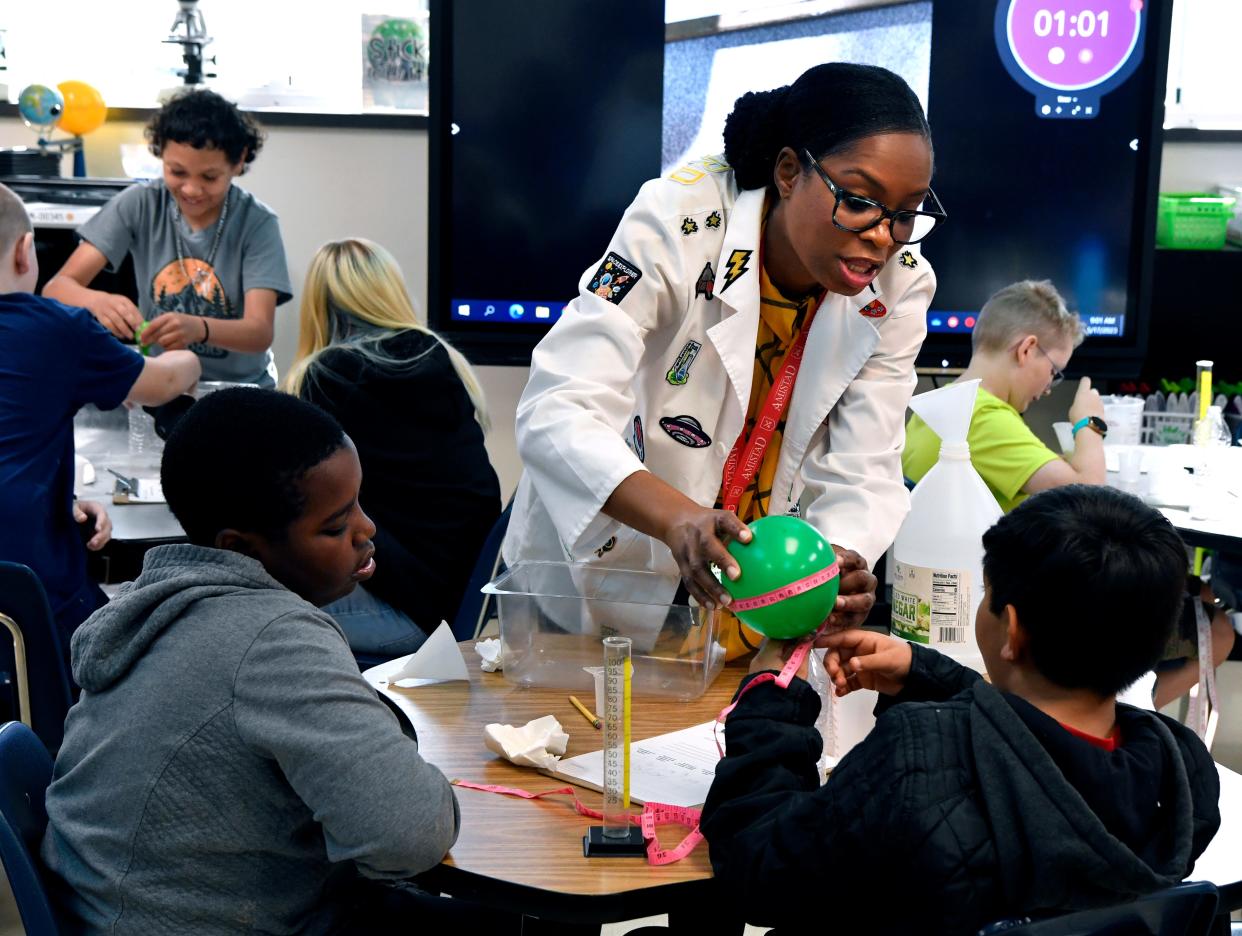 Taniece Thompson-Smith assists a student with measuring the circumference of a balloon during a class experiment at Stafford Elementary School on Wednesday. Thompson-Smith was named the AISD Elementary Teacher of the Year.