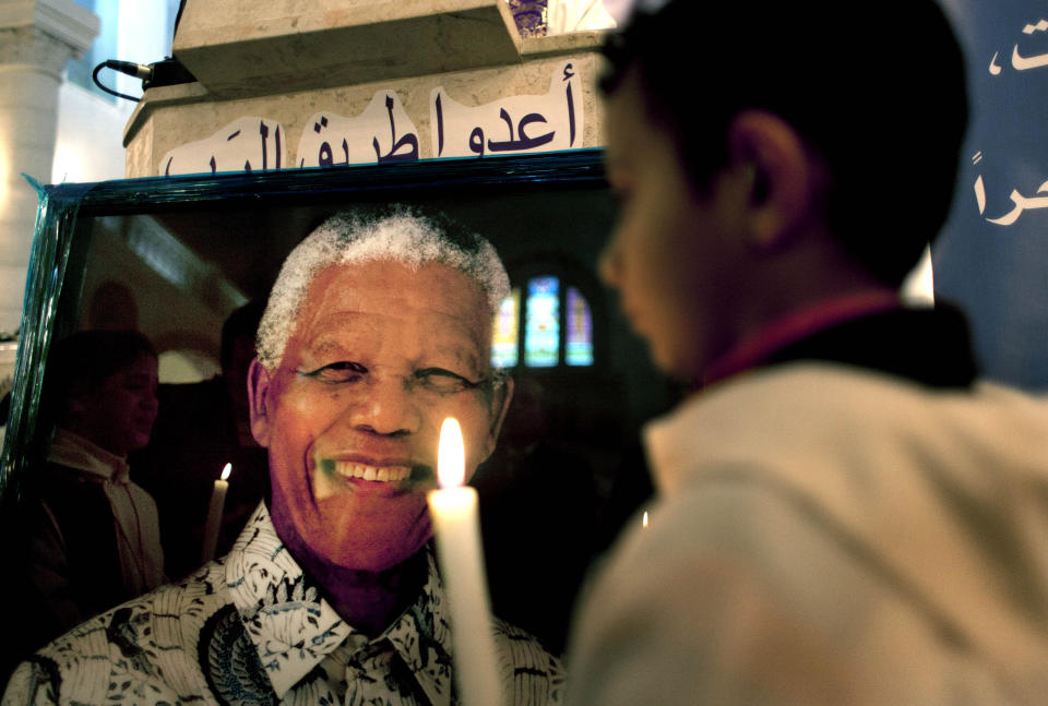 FILE — A Palestinian child holds a lit candle as he prays in front of a poster of late South African leader Nelson Mandela, during a special service in his honor at the Holy Family Church, in the West Bank city of Ramallah, Sunday, Dec. 8, 2013. South Africa's long-held support for the Palestinian people can be traced back to the time of the late Nelson Mandela and Palestinian leader Yasser Arafat, with the two leaders believing that the struggle for freedom by Blacks in apartheid South Africa and Palestinians in Gaza and the West Bank were the same. (AP Photo/Nasser Nasser, File)