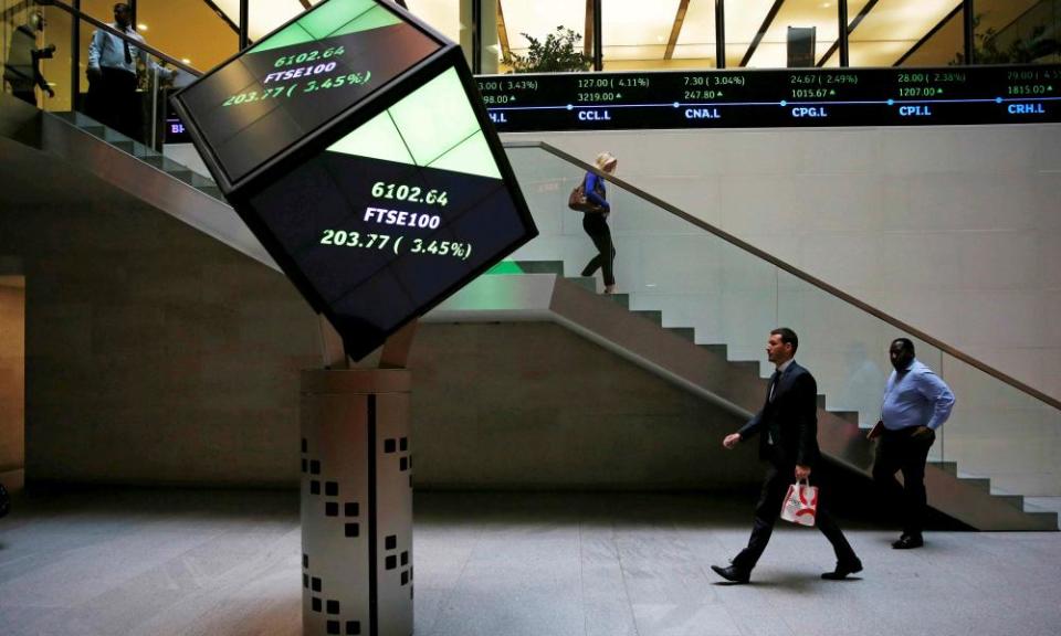 People walk through the lobby of the London Stock Exchange in London