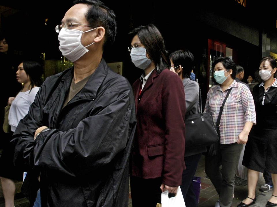 Wearing protective masks, Hong Kong residents line up to get free masks on a Hong Kong downtown street on Friday, March 28, 2003,