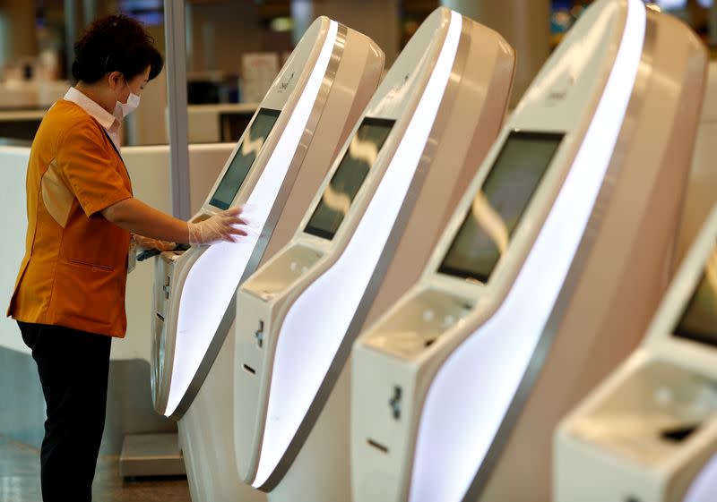 A cleaner wearing a mask in precaution of the coronavirus outbreak cleans self check-in machines at Changi Airport in Singapore