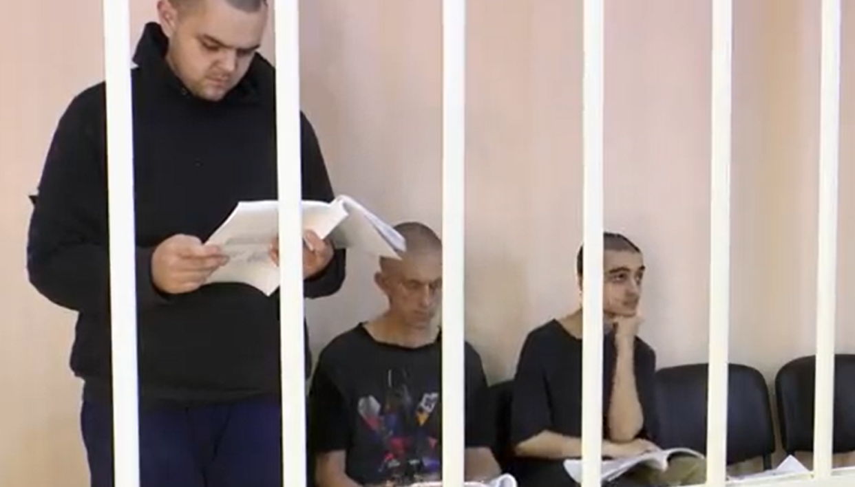 <span class="caption">Les Britanniques Aiden Aslin et Shaun Pinner et le Marocain Brahim Saadoun pendant leur procès. Image tirée d’un enregistrement diffusé par la Cour suprême de la République populaire autoproclamée de Donetsk. </span>