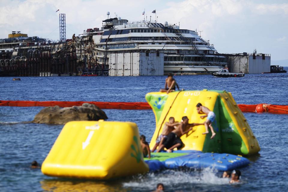 People dive in front of the cruise liner Costa Concordia at Giglio harbour, Giglio Island July 13, 2014. (REUTERS/Alessandro Bianchi)