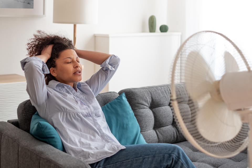 Woman using fan at home. (Getty Images)