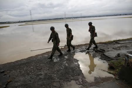 Japanese Self-Defence Force soldiers walk at an area flooded by the Kinugawa river, caused by typhoon Etau in Joso, Ibaraki prefecture, Japan, September 11, 2015. REUTERS/Issei Kato