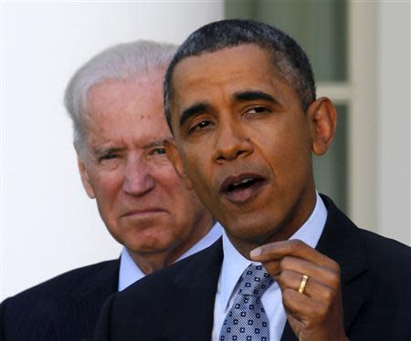 U.S. President Barack Obama stands next to Vice President Joseph Biden (L) while talking about the enrolment numbers of the Affordable Care Act at the White House in Washington, April 1, 2014. REUTERS/Larry Downing