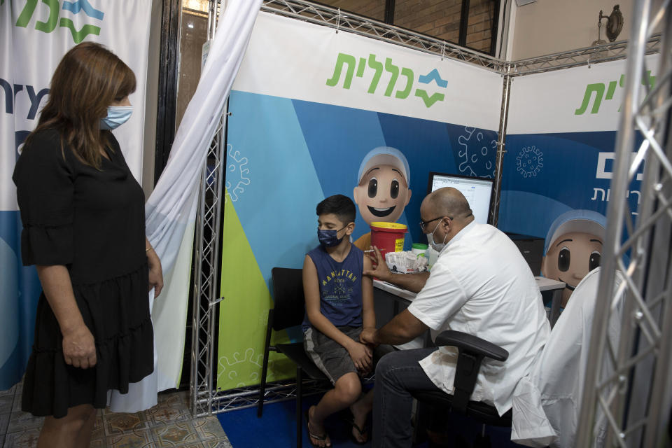 FILE - In this Aug. 15, 2021, file, photo, a 12-year-old boy braces himself as a medical professional prepares to administer the coronavirus vaccine at Clalit Health Services, one of Israel's health maintenance organizations, in Jerusalem. Israel is pressing ahead with its aggressive campaign of offering coronavirus boosters to almost anyone over 12 and says its approach was further vindicated by a U.S. decision to give the shots to older patients or those at higher risk. (AP Photo/Maya Alleruzzo, File)