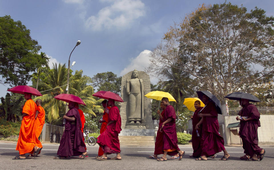 FILE - In this March 4, 2014, file photo, Sri Lankan Buddhist monks walk towards the U.N. office in Colombo, Sri Lanka. The Indian Ocean island nation of Sri Lanka, which will elect a new president on Saturday, Nov. 16, 2019 has had a tumultuous history. Since gaining independence from British colonial rule in 1948, the country has seen three major armed conflicts in which hundreds of thousands have died. It also has had its share of natural disasters. As it prepares to elect its seventh president, Sri Lanka remains a divided nation, with ethnic, political and economic issues unresolved. (AP Photo/Eranga Jayawardena, File)