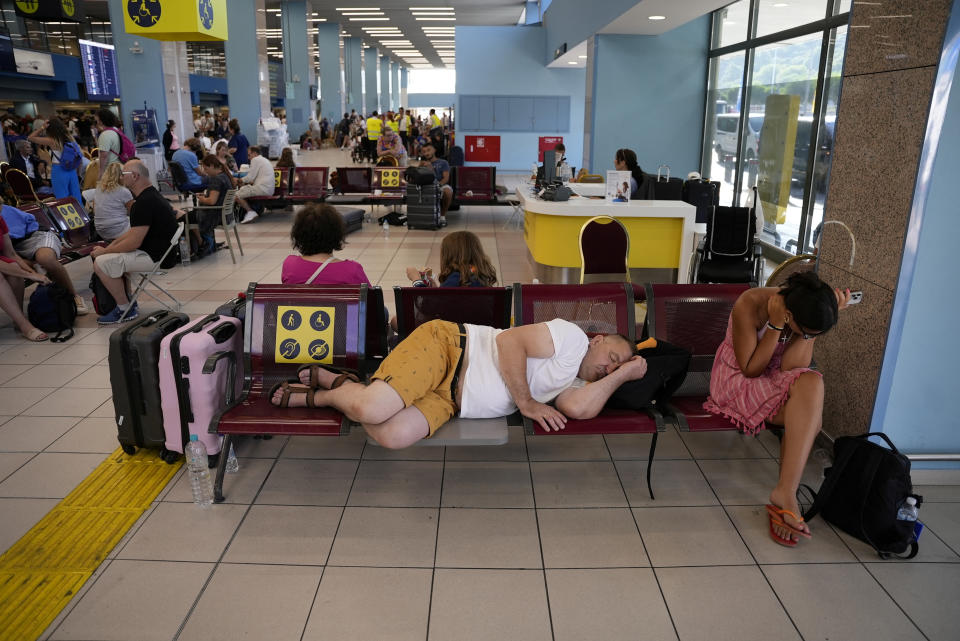 A man sleeps as tourists wait for departing planes at the airport, after being evacuated following a wildfire on the island of Rhodes, Greece, July 24, 2023. REUTERS/Fedja Grulovic