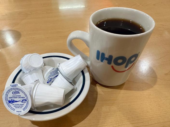 white and blue cup of IHOP coffee with bowl of creamer on the side