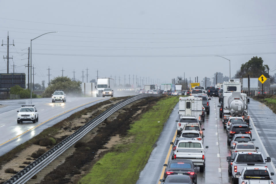 Cars are stopped in the northbound lanes of Highway 101 after flooding closed the highway near Chualar, Calif., Tuesday, Dec. 27, 2022. The first in a week of storms brought gusty winds, rain and snow to California on Tuesday, starting in the north and spreading southward. (AP Photo/Nic Coury)