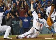 Oct 16, 2018; Los Angeles, CA, USA; Los Angeles Dodgers shortstop Manny Machado (8) celebrates with catcher Yasmani Grandal (9) after scoring on an RBI single by center fielder Cody Bellinger (not pictured) defeat the Milwaukee Brewers in the thirteenth inning in game four of the 2018 NLCS playoff baseball series at Dodger Stadium. Mandatory Credit: Richard Mackson-USA TODAY Sports