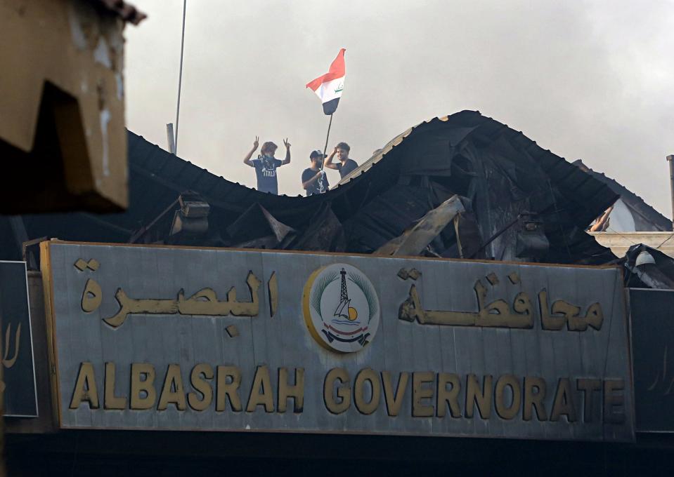 Protesters raise the Iraqi flag over Basra Government building during a demonstration demanding better public services and jobs in Basra, 340 miles (550 km) southeast of Baghdad, Iraq, Friday, Sept. 7, 2018. Hundreds of angry protesters in Basra took to the streets on Thursday night. Some clashed with security forces, lobbing Molotov cocktails and setting fire to a government building as well as the offices of Shiite militias. At least three people were shot dead in confrontations with security forces. (AP Photo/Nabil al-Jurani)